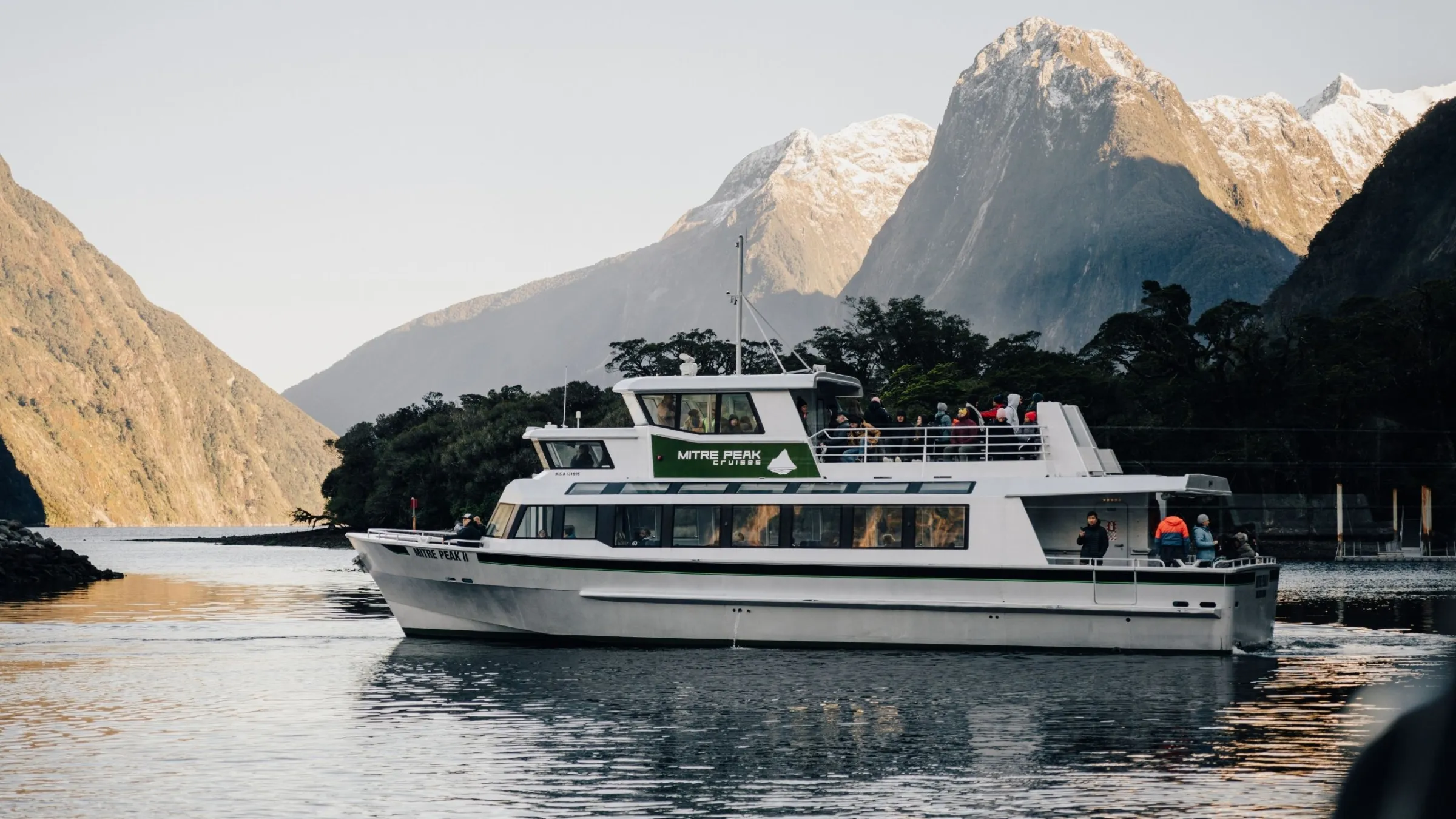 a boat in the water with Milford Sound in the background
