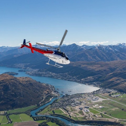 a plane flying over a body of water with a mountain in the background