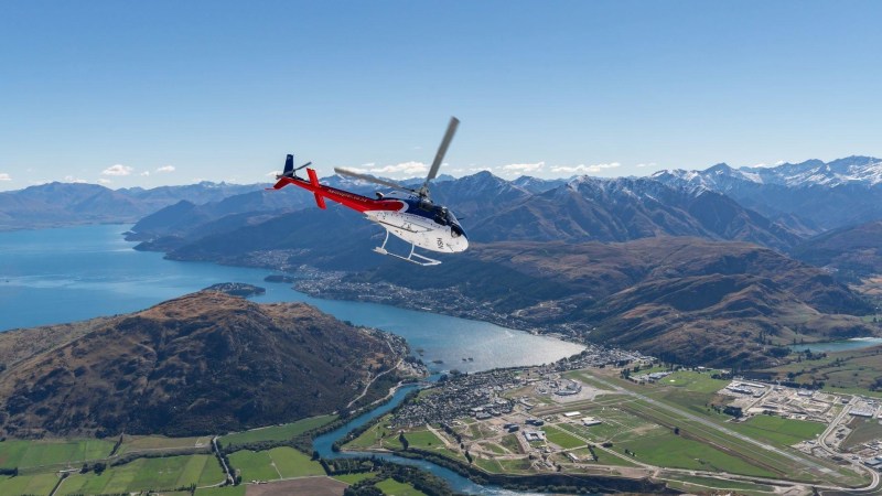 Heli Cruise Heli from Queenstown Image 1 a plane flying over a body of water with a mountain in the background